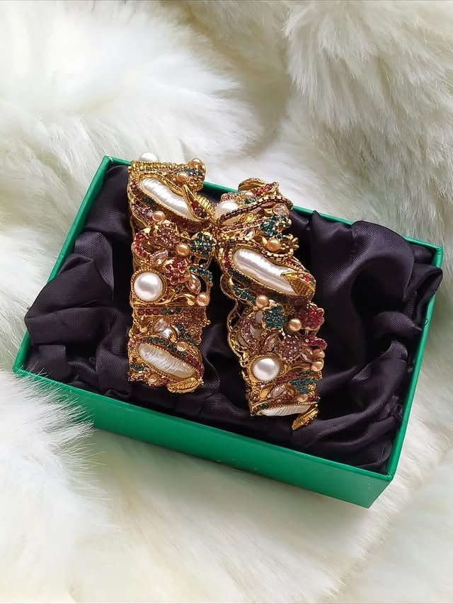 Decorative bow with pearls and gemstones in a green box on a white fur background